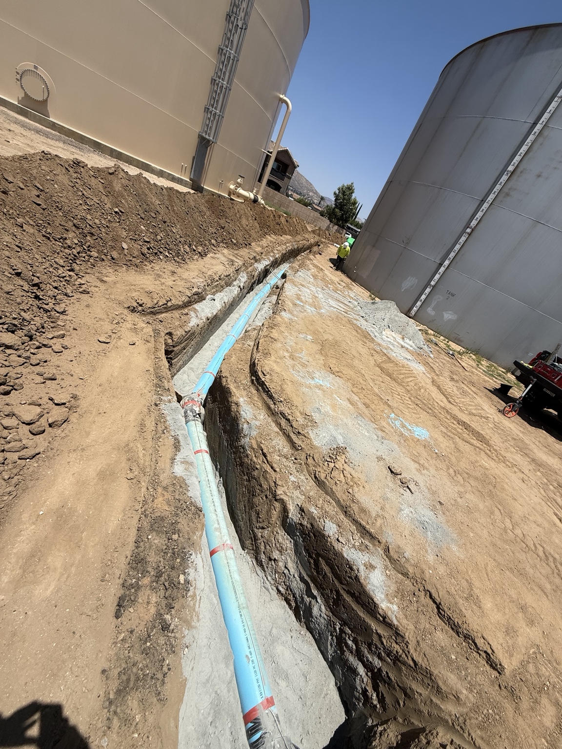 Blue water main installed alongside water tanks